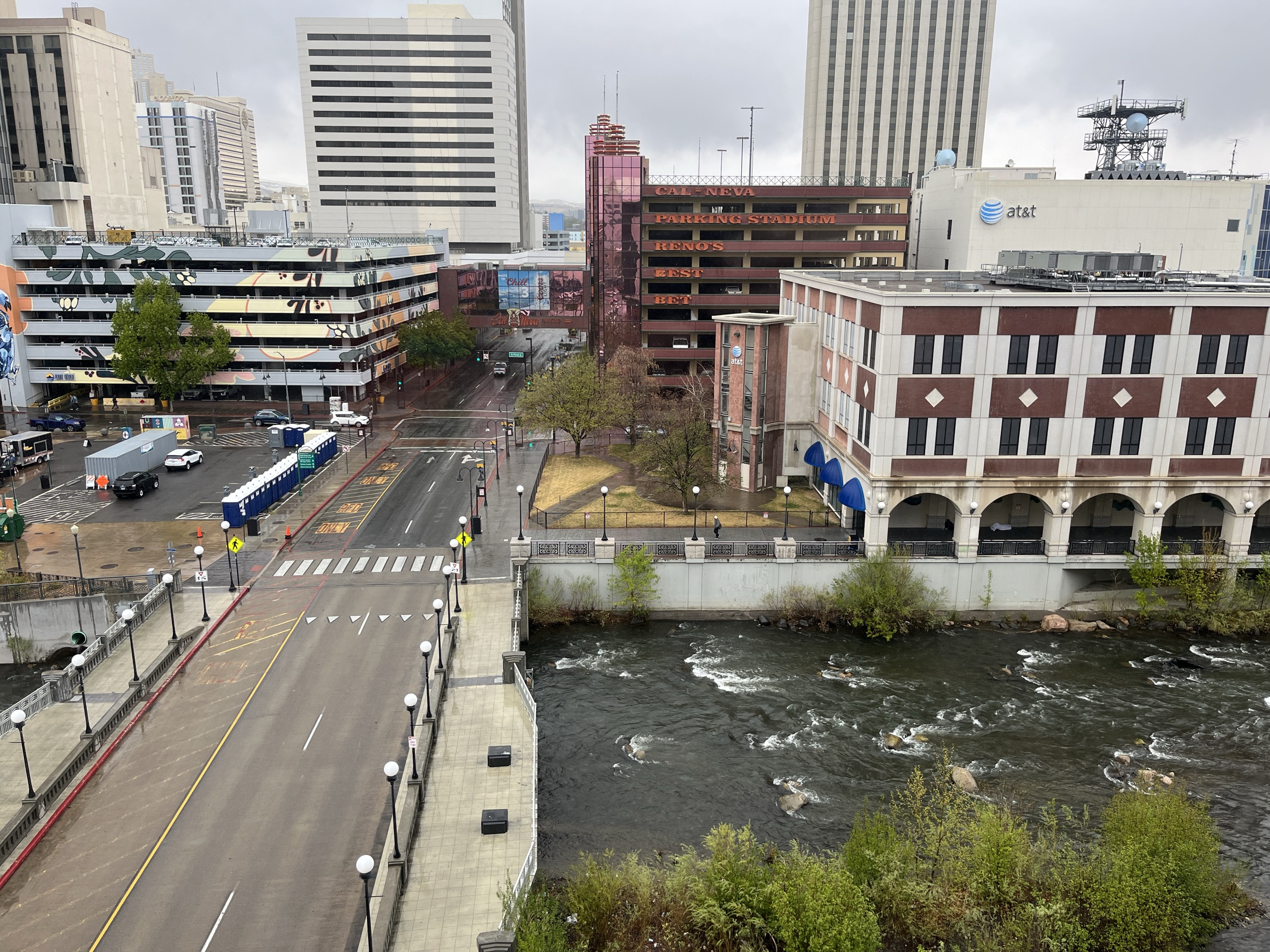 Downtown Reno from a hotel window — the Truckee River below, parking garage and AT&T tower across the street, low grey sky